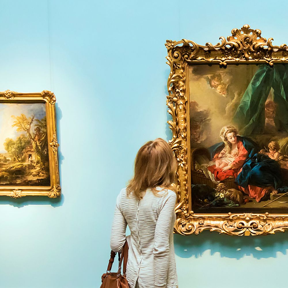 Une visiteuse prend le temps de regarder des tableaux dans une galerie